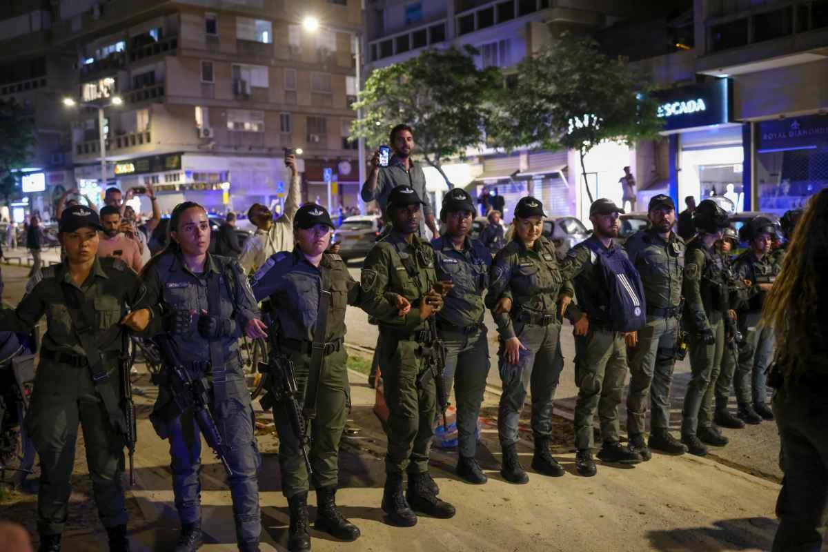 Police stand guard outside a Tel Aviv salon where protesters demonstrating against the government's planned judicial overhaul amassed on March 1, 2023, after learning that the prime minister's wife, Sara Netanyahu, was getting her hair done inside. (AP Photo/Oren Ziv)