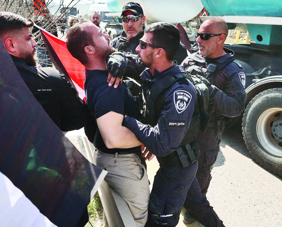 An Israeli police officer scuffles with a protester as Palestinian and Israeli peace activists demonstrate at the entrance of Hawara in the occupied West bank. (AFP)