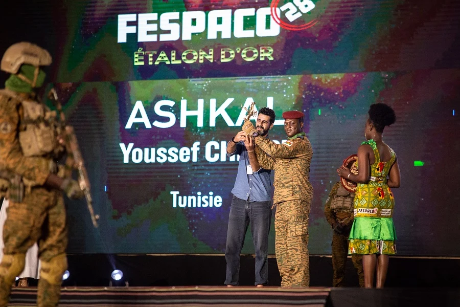 A man (2nd L) representing the Tunisian director Youssef Chebbi, receives from Burkina Faso military leader Captain Ibrahim Traore (3rd L) the Etalon d'Or won for the film ‘Ashkal’ during the closing ceremony of the 28th Pan-African Film and television Festival. (AFP)