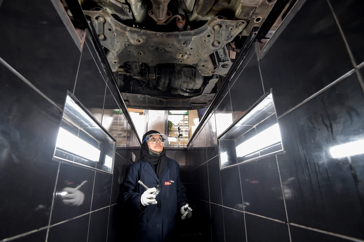 A Saudi mechanic walks in the inspection trench beneath a vehicle at a repair and service center. (Supplied)