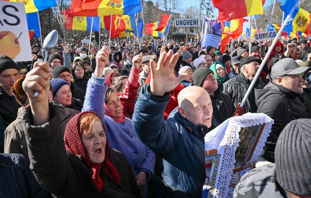 Moldovan demonstrators put their hands in the air and hold Moldova national flags during a protest organized by a Moldovan member of parliament on behalf of the "Sor" opposition party in Chisinau on March 12, 2023. (AFP)