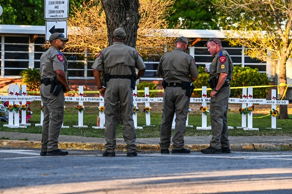 Police officers stand near a makeshift memorial for the shooting victims at Robb Elementary School in Uvalde, Texas, on May 26, 2022. (AFP)