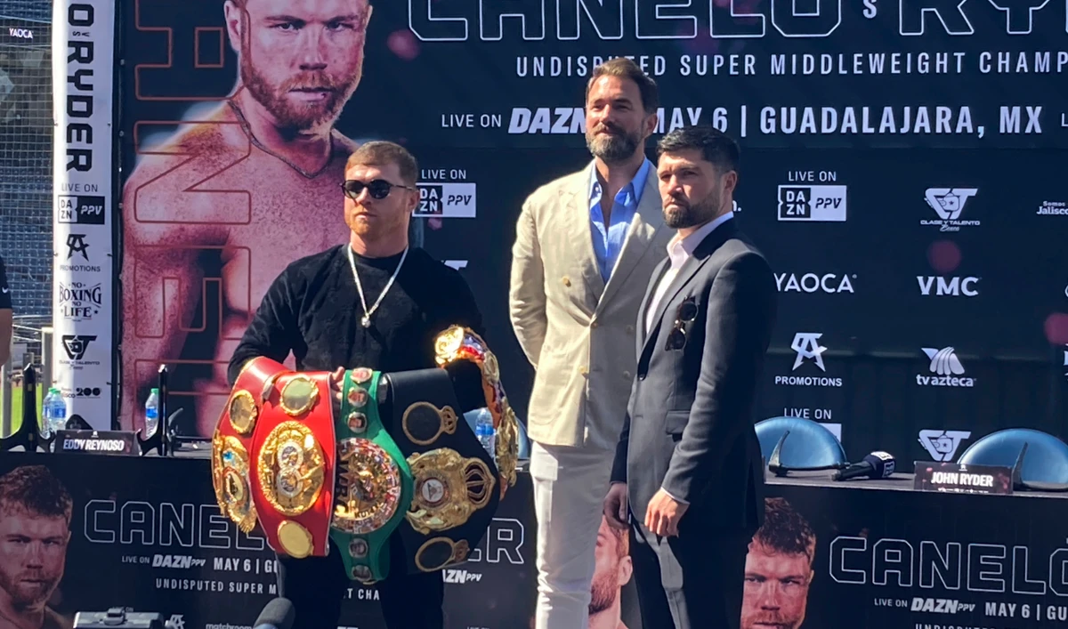 Saul Canelo Alvarez, left, holds up his collection of super middleweight championship belts after facing off with challenger John Ryder, right, of Britain, during a news conference in San Diego on Thursday. (AP)