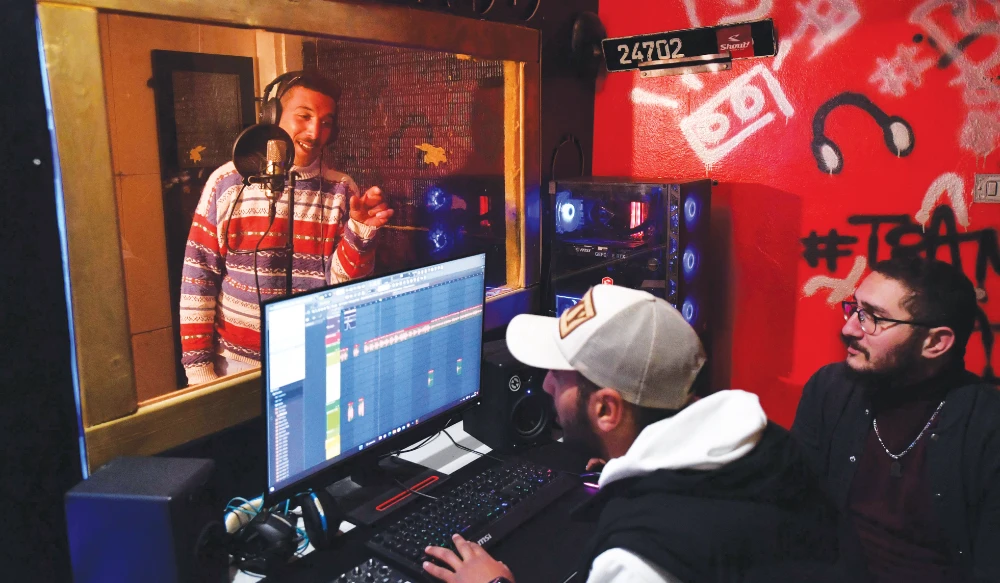 Mohamed Ali Ayari, left, a rapper from a down-at-heel Tunis district, records a song in a booth at a recording studio in Daouar Hicher. (AFP)