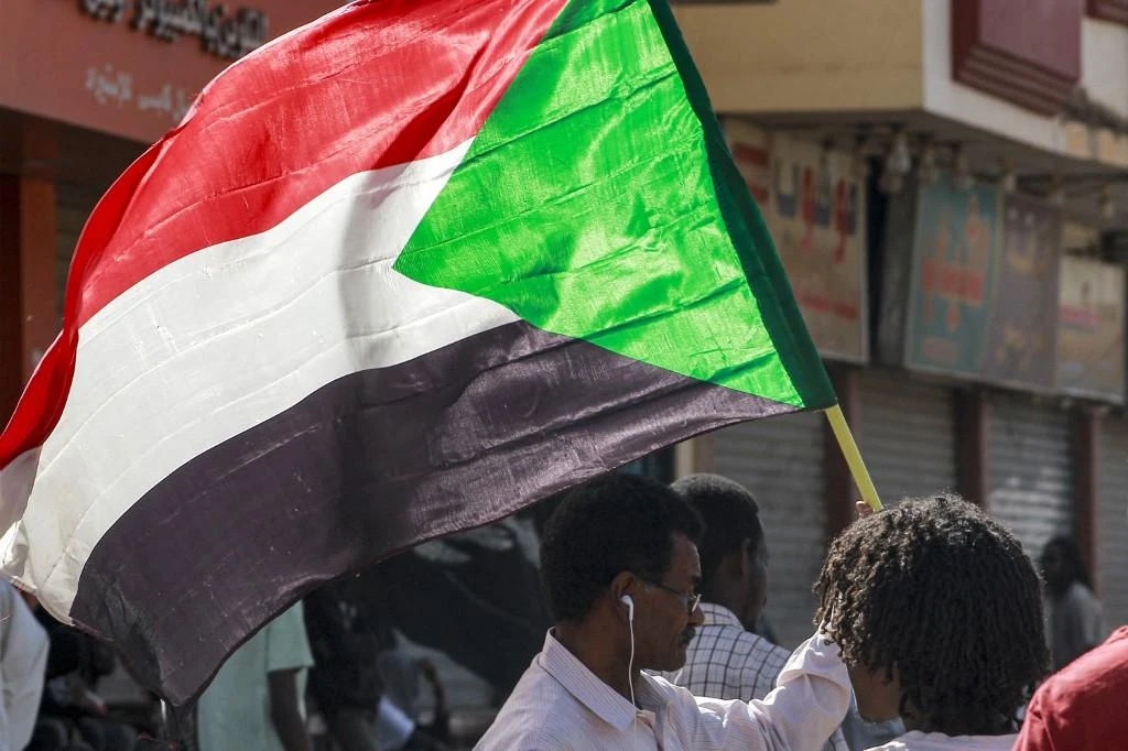 (File/AFP A man waves a Sudanese national flag while taking part in a protest march. (File/AFP)