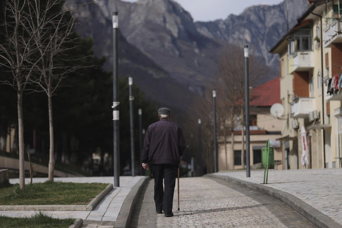 An old man walks on a pedestrian street in the city center of Bajram Curri, 240 kilometers north of Tirana, Albania, Tuesday, March 14, 2023. (AP Photo)