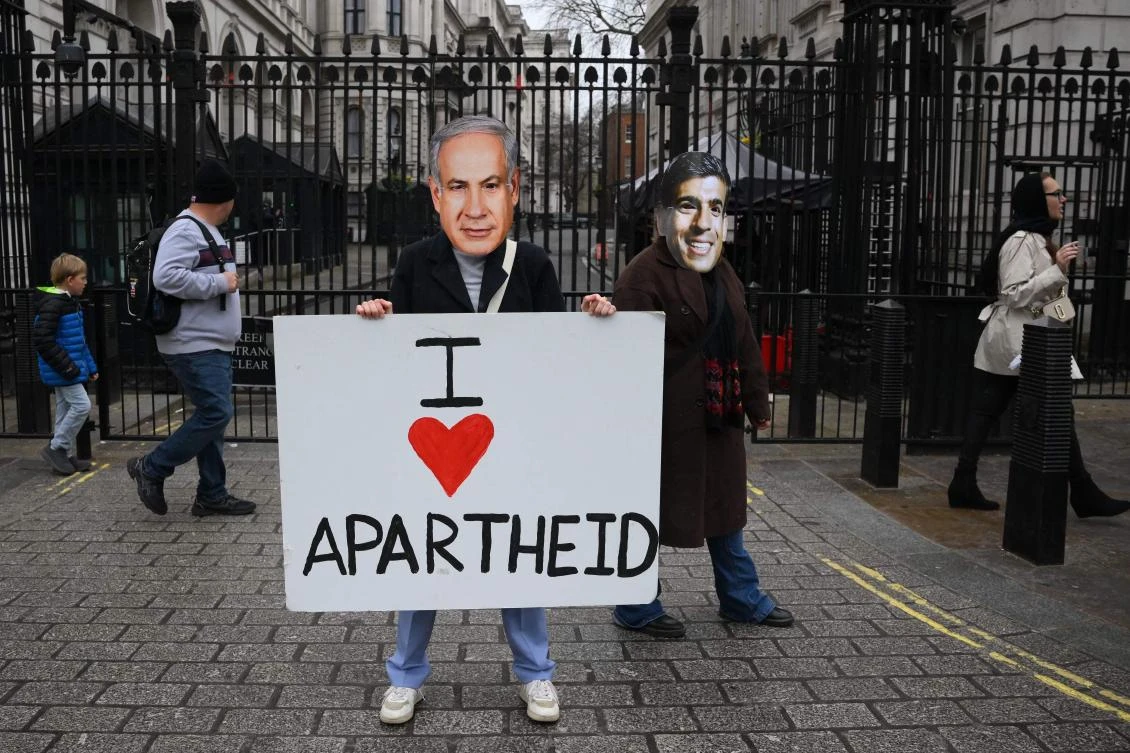 Protesters wearing facemasks of Israel’s Prime Minister Benjamin Netanyahu and Britain’s Prime Minister Rishi Sunak stand with a placard outside the gates of Downing Street in central London on Mar. 23, 2023. (AFP)