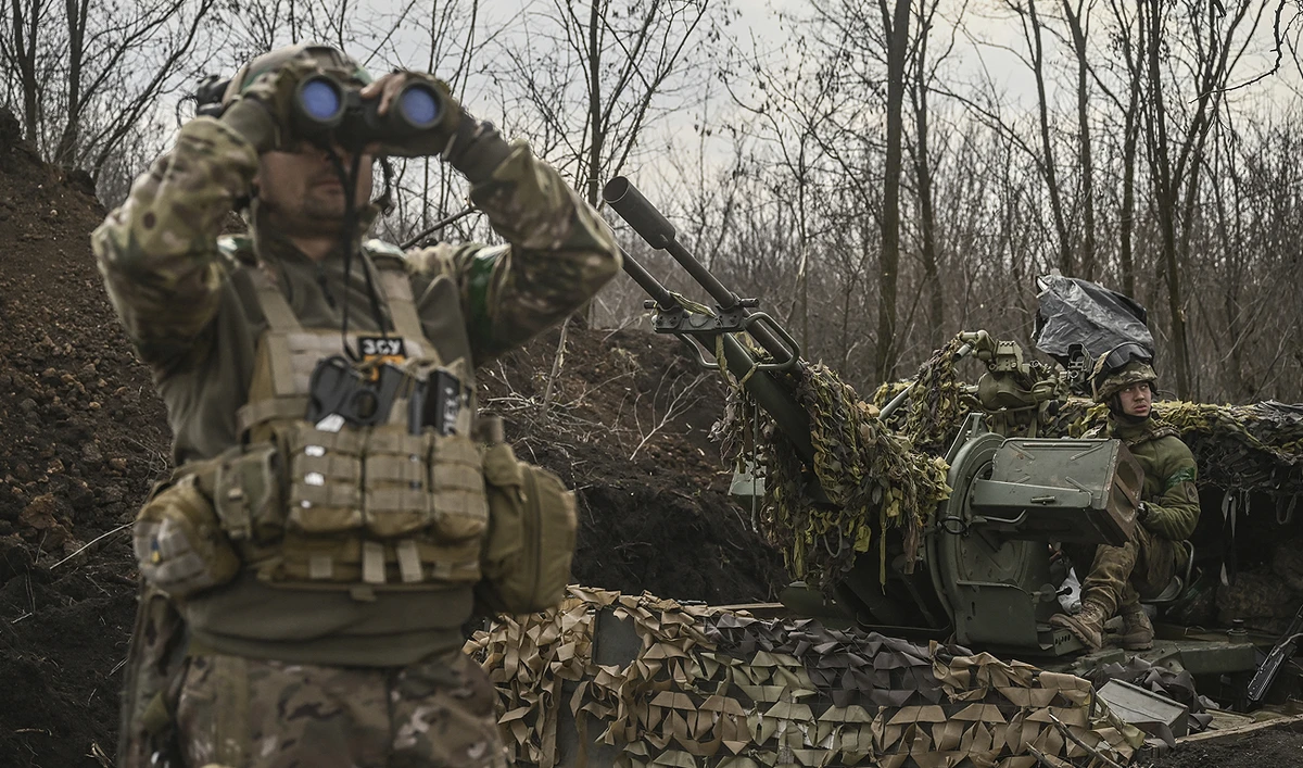 A Ukrainian serviceman (L) looks on with binoculars next to another (R) sitting on an anti-air gun near Bakhmut, on March 24, 2023. (Photo courtesy: AFP)