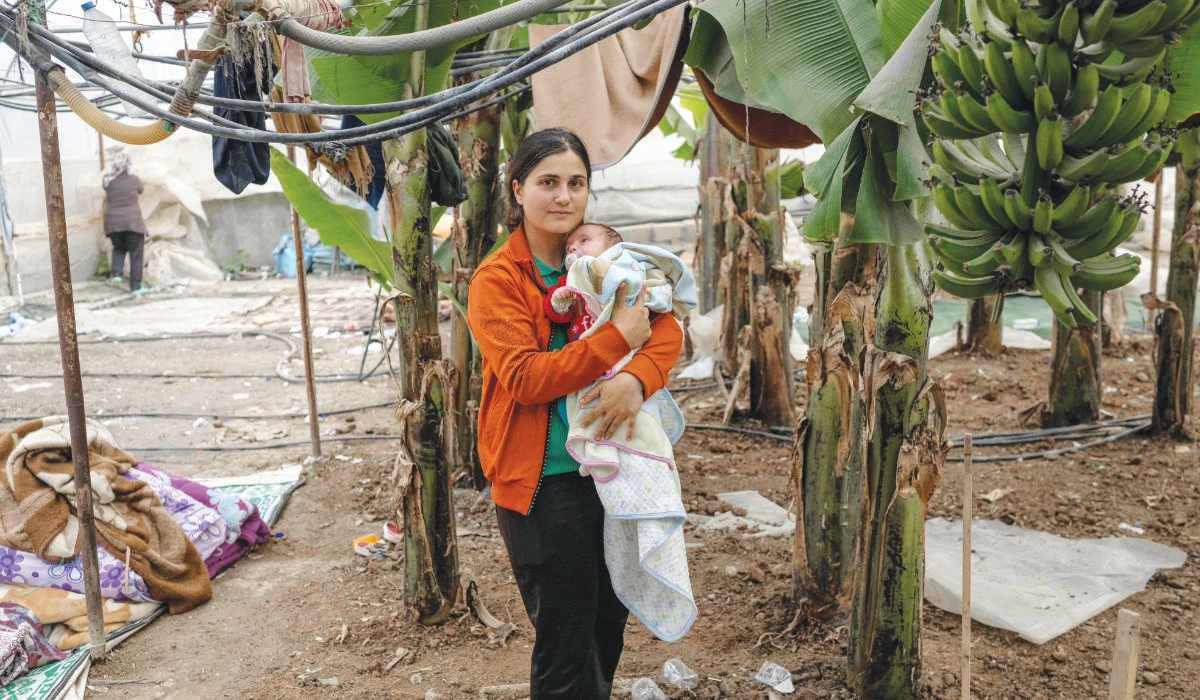 Ozlem Yildirim with her child at a banana plantation in the quake-hit town of Samandag, southern Turkey, where she lives. (AFP)