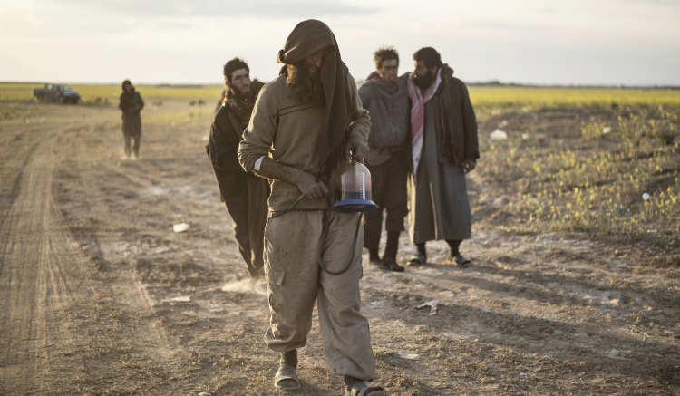 Men suspected of being Daesh group fighters walk together towards a screening point in Deir Ezzor province, Syria. (AFP)
