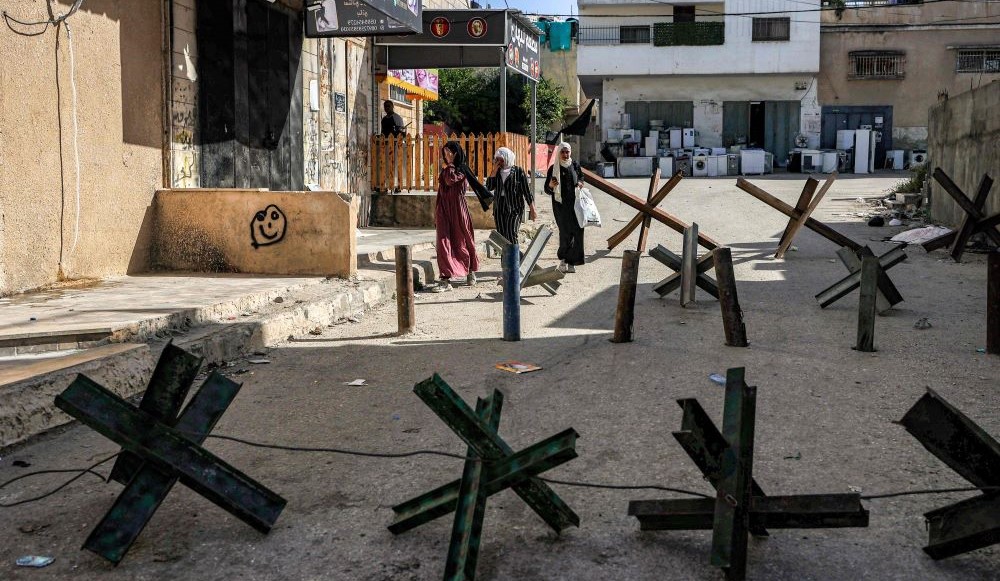 Women walk past anti-vehicle obstacles in Jenin camp for Palestinian refugees, West Bank, Apr. 18, 2023. (AFP)