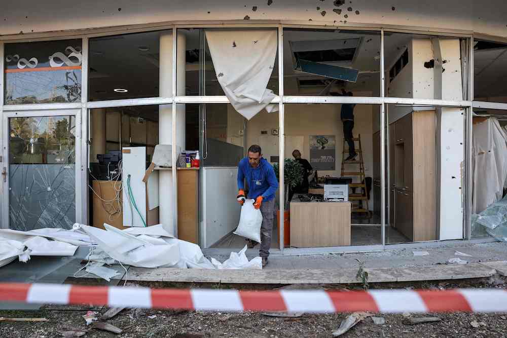 People remove debris in a building damaged in the aftermath of intercepted rocket fire launched from Lebanon and intercepted by Israel in its northern town of Shlomi. (AFP)