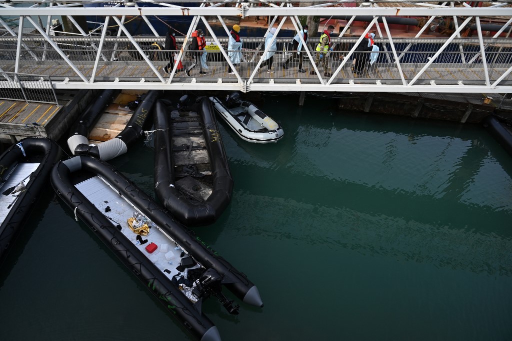 Walking above inflatable dinghies used by migrants, members of the British military help a group of migrants at the port of Dover after they disembark, having been picked up crossing the English Channel from France on April 14, 2022, at Dover, on the south-east coast of England. (AFP)