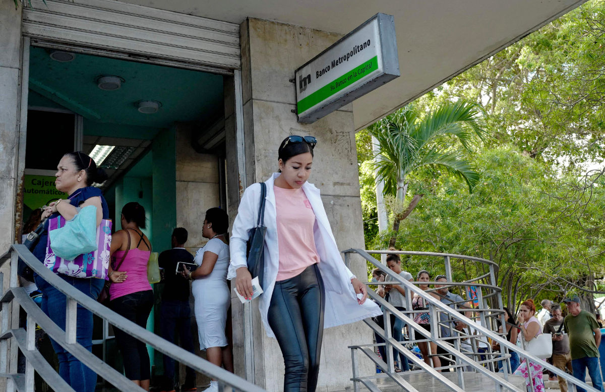 A woman walks out of a bank in Havana, on April 11, 2023, a day after the Cuban government announced a surprise reversal of a US dollar deposit ban. (AFP)