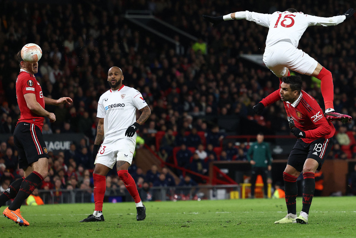 Sevilla's Moroccan forward Youssef En-Nesyri headers ball to score a second goal, deflected in for an own goal off Manchester United's English defender Harry Maguire (L) during their UEFA Europa league quarterfinal first leg at Old Trafford stadium on Thursday. (AFP)