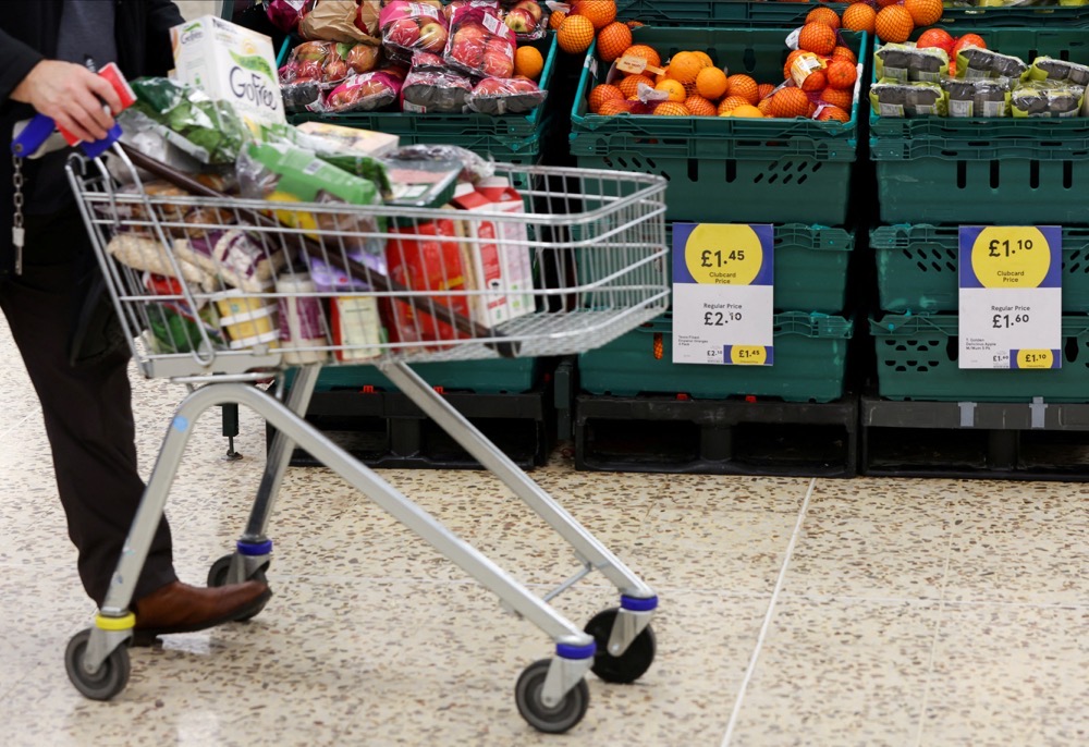 A person pushes a shopping cart next to the clubcard price branding inside a branch of a Tesco Extra Supermarket in London, Britain. (AFP)