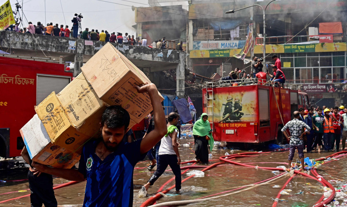A worker carries goods after a fire broke out at a market in Dhaka on Saturday. (AFP)