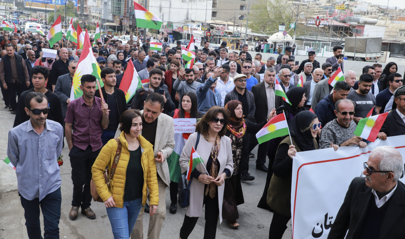 People lift banners and Kurdish flags during a demonstration in Sulaimaniyah in the autonomous Kurdish region of northern Iraq, on April 9, 2023, to protest reported Turkish bombardment of an airport in the region two days earlier. (AFP/File)