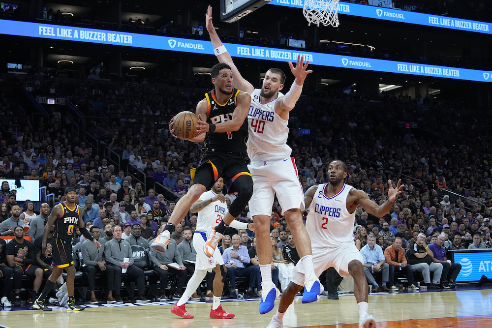 Phoenix Suns guard Devin Booker dishes off as Los Angeles Clippers center Ivica Zubac defends during the second half of Game 2 of a first-round NBA basketball playoff series Tuesday in Phoenix. (AP)