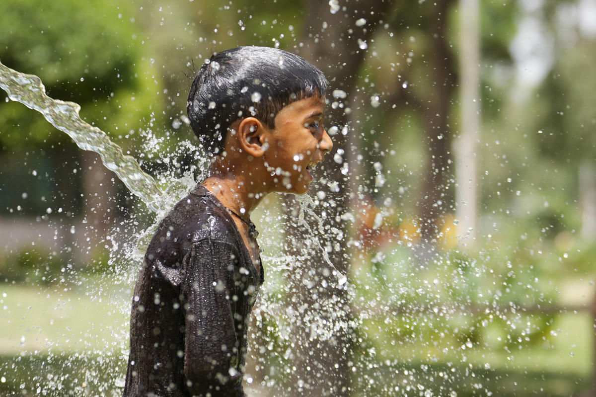 A boy cools himself under an irrigation water pipe as northern Indian continues to reel under intense heat wave in Lucknow in the the Indian state of Uttar Pradesh, Wednesday, April 19, 2023. (AP)