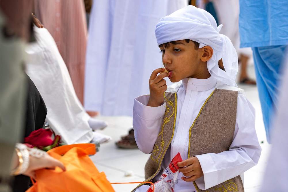 A boy eats sweets at the Grand Mosque in the holy city of Makkah on the first day of Eid Al-Fitr, which marks the end of the holy fasting month of Ramadan, on April 21, 2023. (AFP)