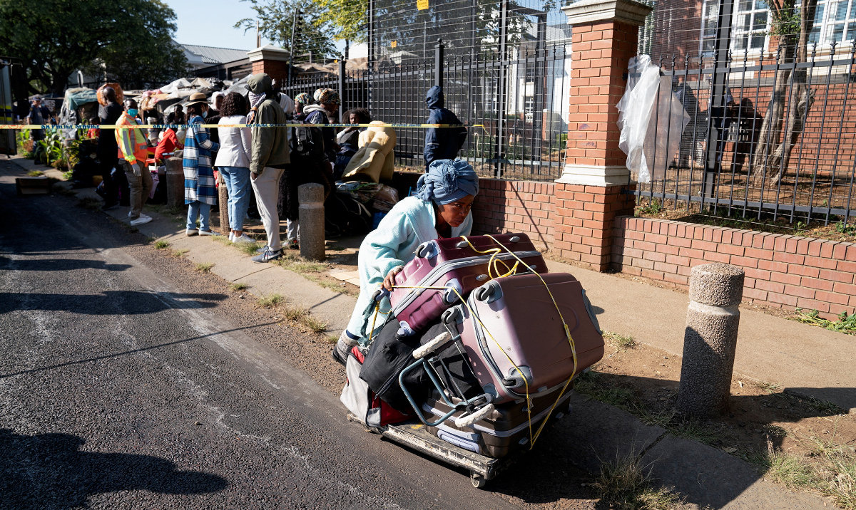 A woman carries luggages in Pretoria, South Africa, on Friday as police forced out and detained refugees from various African countries, who had been staying in makeshift shelters outside the UNHCR office since 2019. (Reuters)