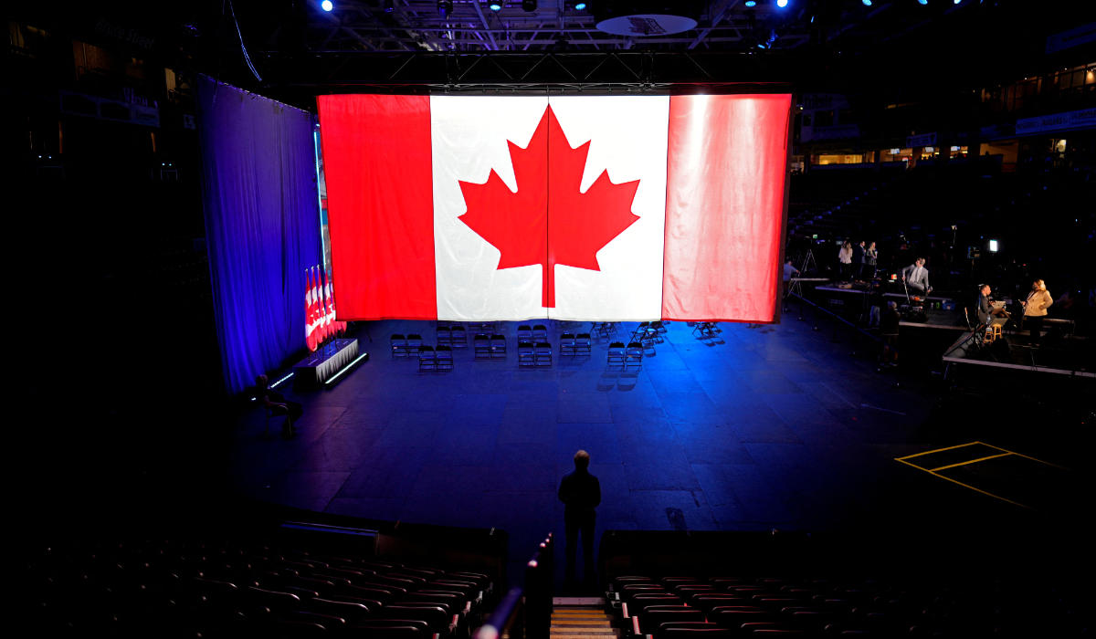 A man stands under a giant Canadian flag before the Conservative election party at the Conservative party headquaters, in Oshawa, Ontario, Canada September 20, 2021. (REUTERS)