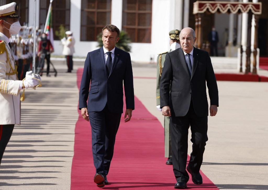 French President Emmanuel Macron walks with Algeria's President Abdelmadjid Tebboune at Algiers airport, in Algiers, on August 27, 2022. (AFP)
