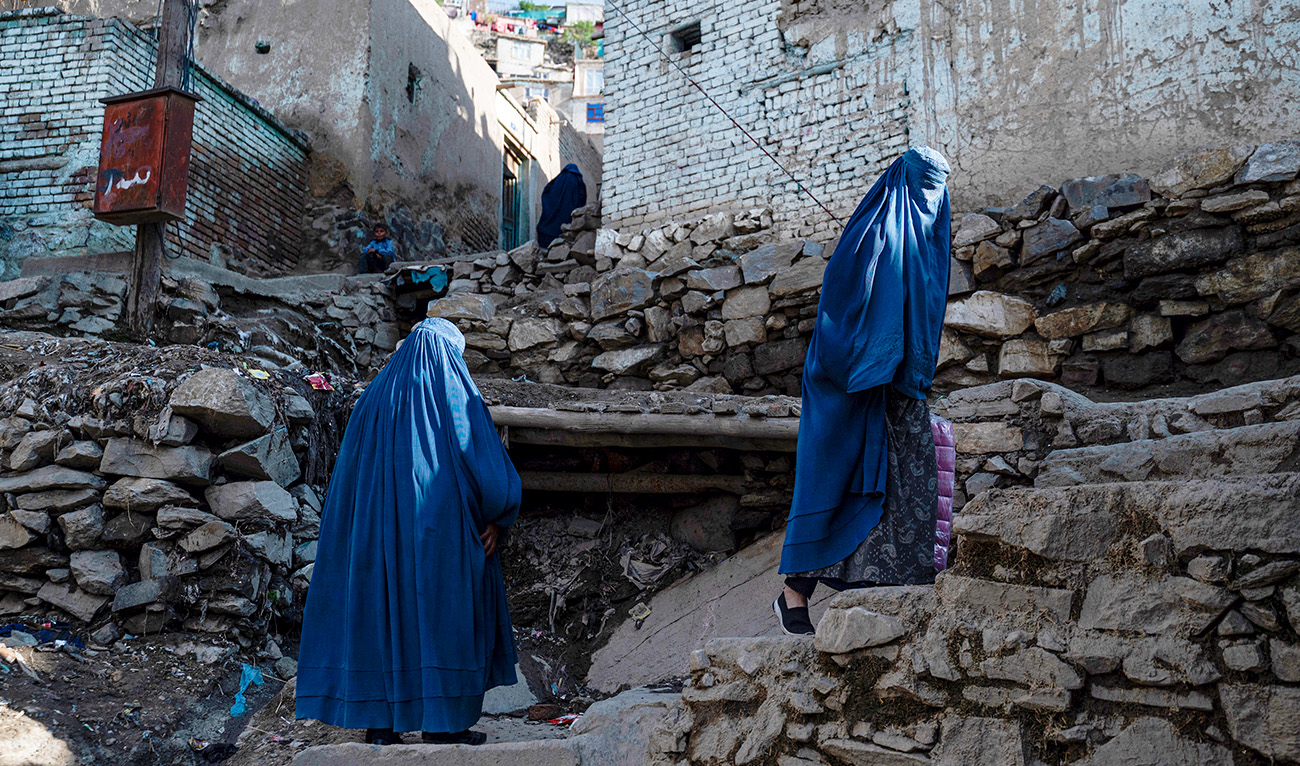 Afghan burqa-clad women climb a stony path in the Shōr Bāzār area of Kabul on April 6, 2023. (AFP/FILE)