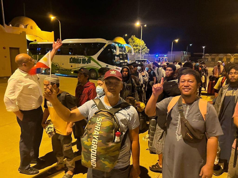 The Philippine ambassador to Egypt, Ezzedin Tago, far left, welcomes the first batch of Filipinos evacuated from Sudan as they cross the Egyptian border on April 27, 2023. (Philippine Department of Foreign Affairs)