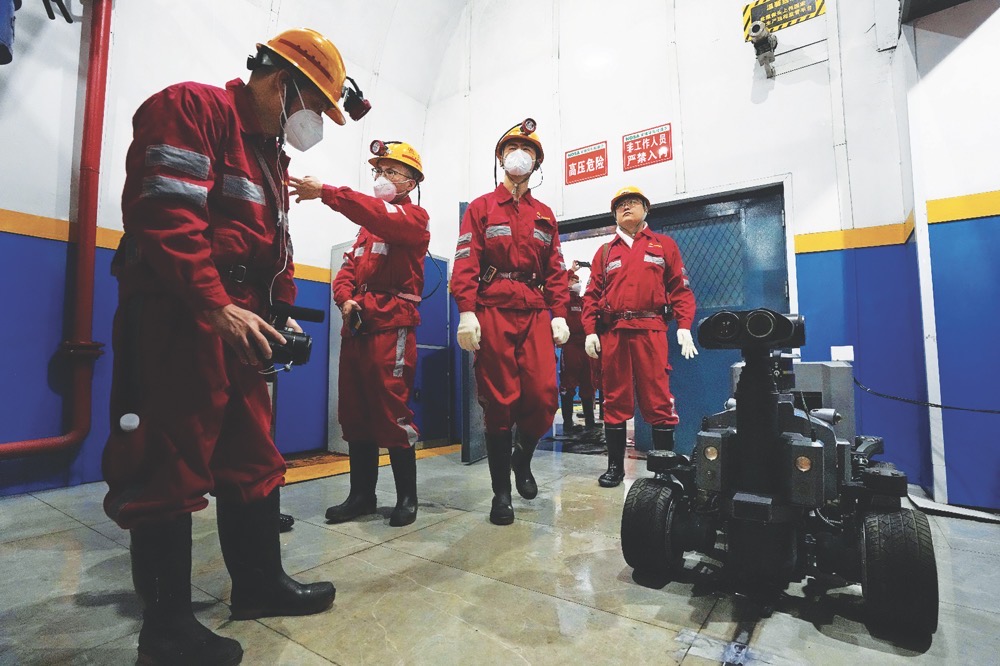 Workers stand near an autonomous robot used to monitor equipment at the Hongliulin Coal Mine complex in northwestern China’s Shaanxi province on Tuesday. (AP)