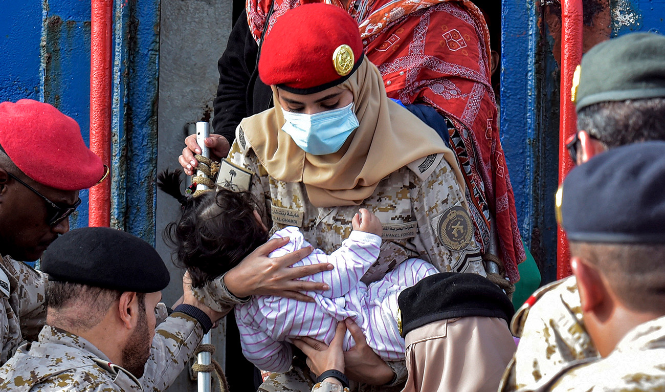 A Saudi Navy sailor carries a child while disembarking off a ferry passenger ship after arrival at King Faisal navy base in Jeddah on April 26, 2023 following a rescue operation amid a US-brokered ceasefire between the country's warring generals.