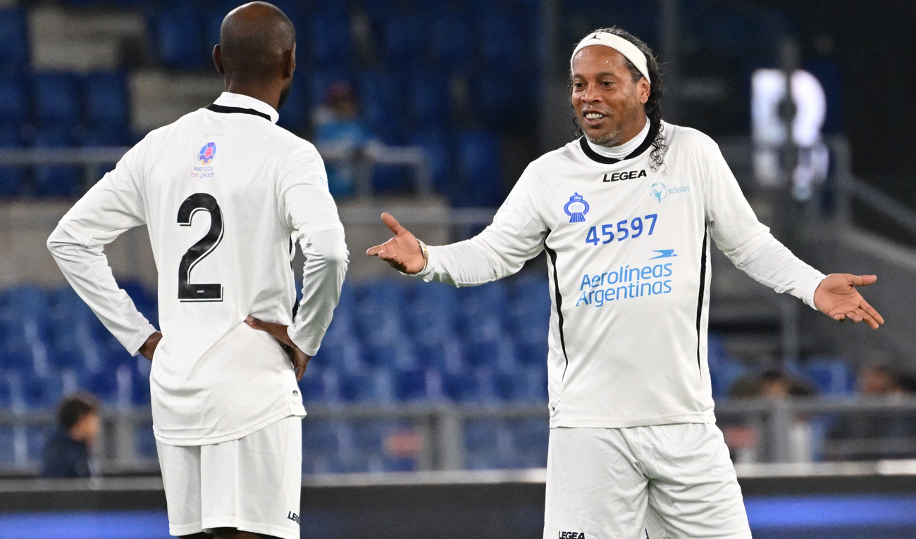 Former Brazilian player Ronaldinho (R) talks to former French player Eric Abidal during a friendly tribute "match for peace" in memory of late Argentininan player Diego Maradona, on November 14, 2022 at the Olympic stadium in Rome. (Photo courtesy: AFP)