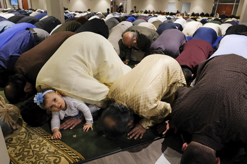 Samar Mansour, peeks out from the arms of her father, Ahmed Mansour, as he prays during the Islamic Society of North West Ohio Eid celebration. (AP)