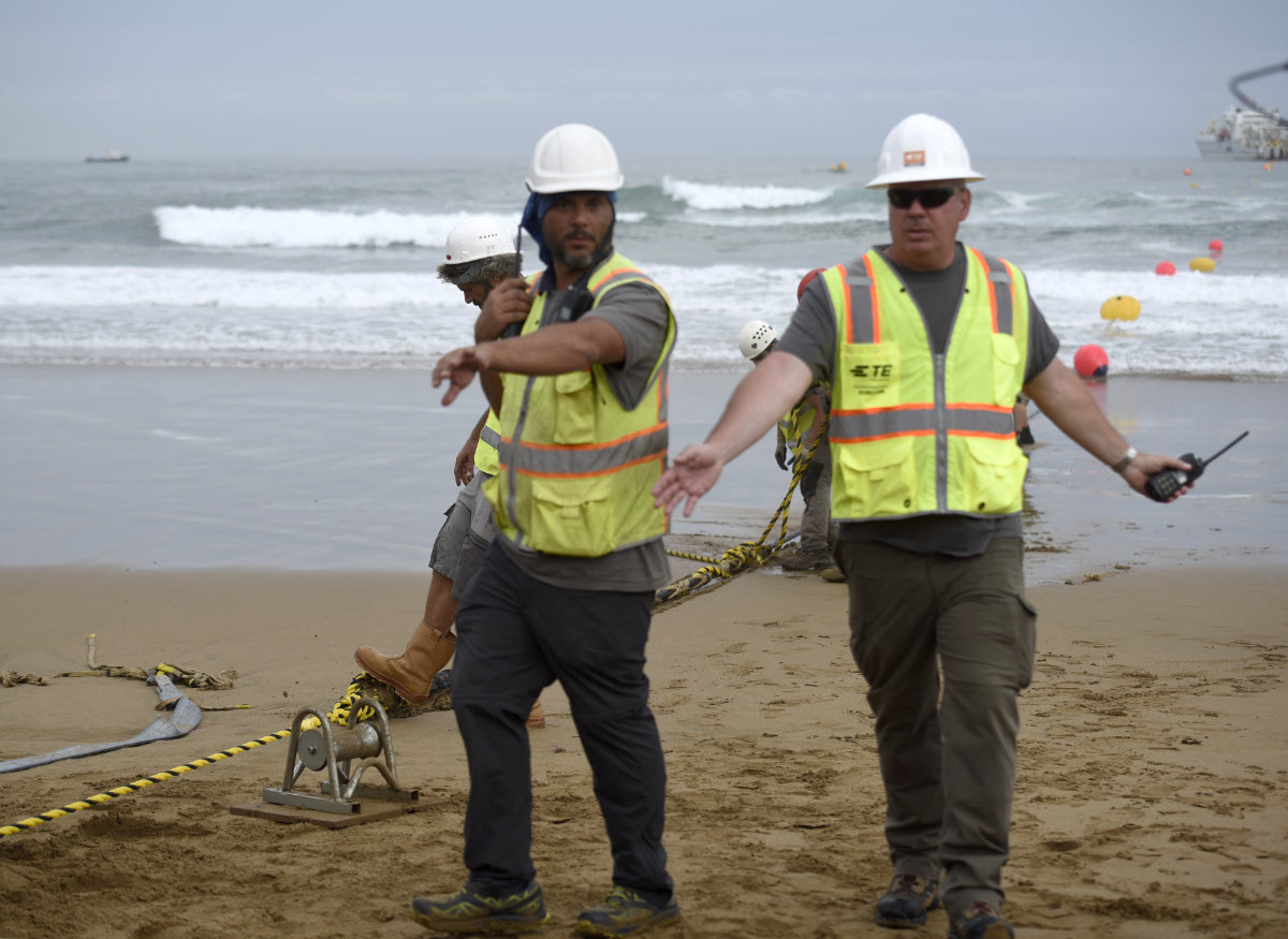 Operators lay an undersea fiber optic cable at Arrietara beach near the Spanish village of Sopelana on June 13, 2017. (AFP)