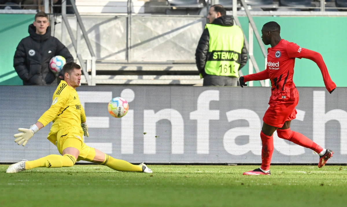 Frankfurt's Randal Kolo Muani, right, scores past Berlin goalkeeper Lennart Grill, during the German Soccer Cup quarterfinal match between Eintracht Frankfurt and Union Berlin, in Frankfurt Tuesday. (AP)
