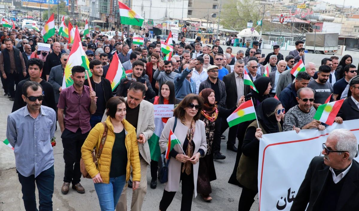 People lift banners and Kurdish flags during a demonstration in Sulaimaniyah in the autonomous Kurdish region of northern Iraq, on April 9, 2023, to protest reported Turkish bombardment of an airport in the region two days earlier. (AFP/File)
