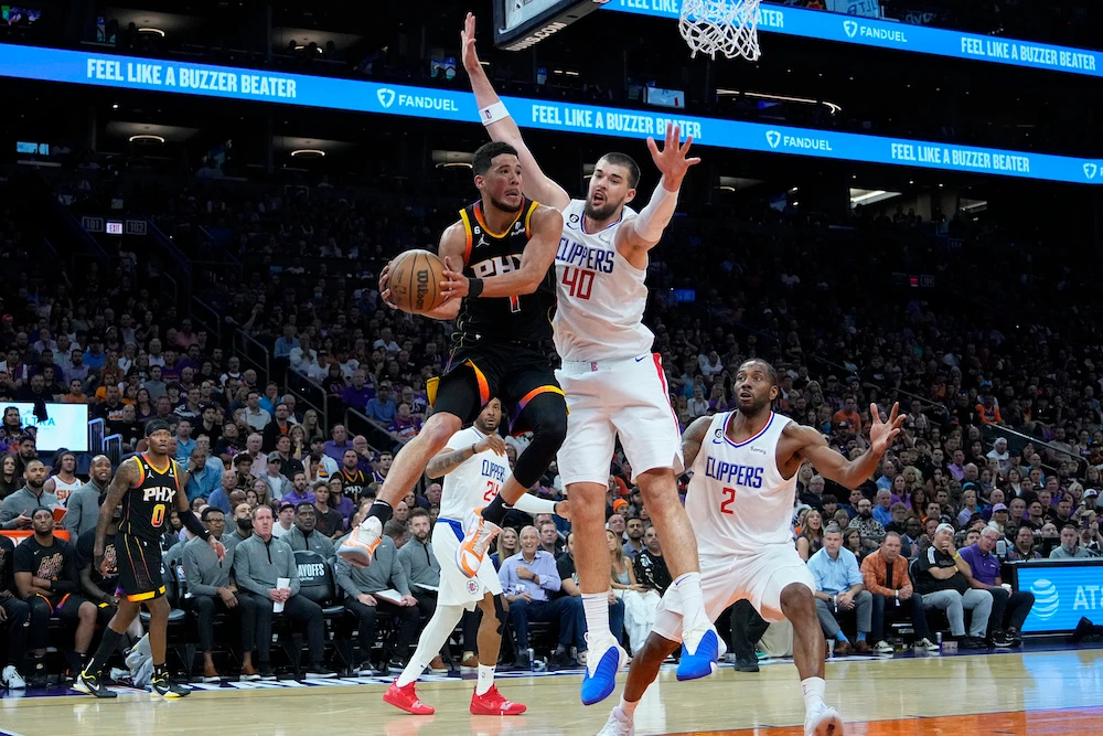 Phoenix Suns guard Devin Booker dishes off as Los Angeles Clippers center Ivica Zubac defends during the second half of Game 2 of a first-round NBA basketball playoff series Tuesday in Phoenix. (AP)