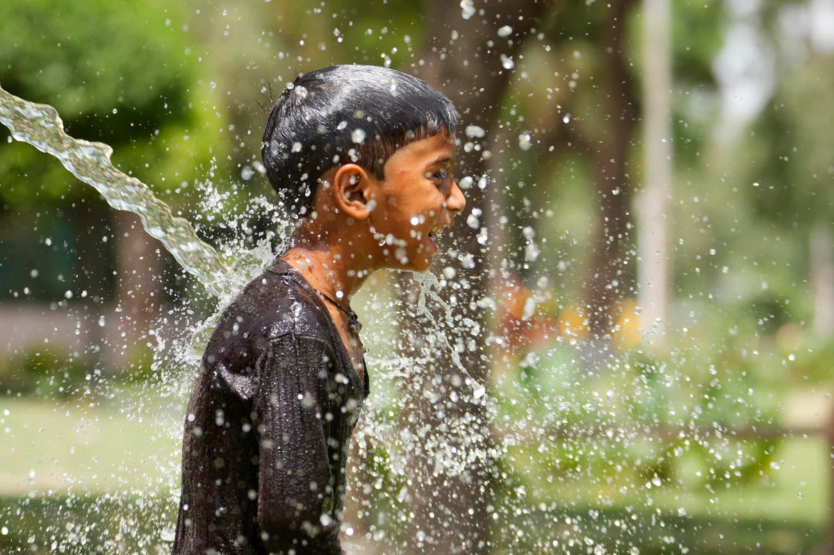 A boy cools himself under an irrigation water pipe as northern Indian continues to reel under intense heat wave in Lucknow in the the Indian state of Uttar Pradesh, Wednesday, April 19, 2023. (AP)