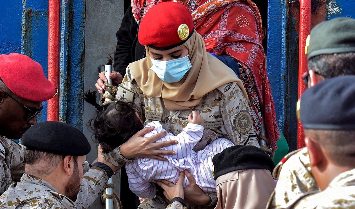 A Saudi Navy sailor carries a child while disembarking off a ferry passenger ship after arrival at King Faisal navy base in Jeddah on April 26, 2023 following a rescue operation amid a US-brokered ceasefire between the country's warring generals.