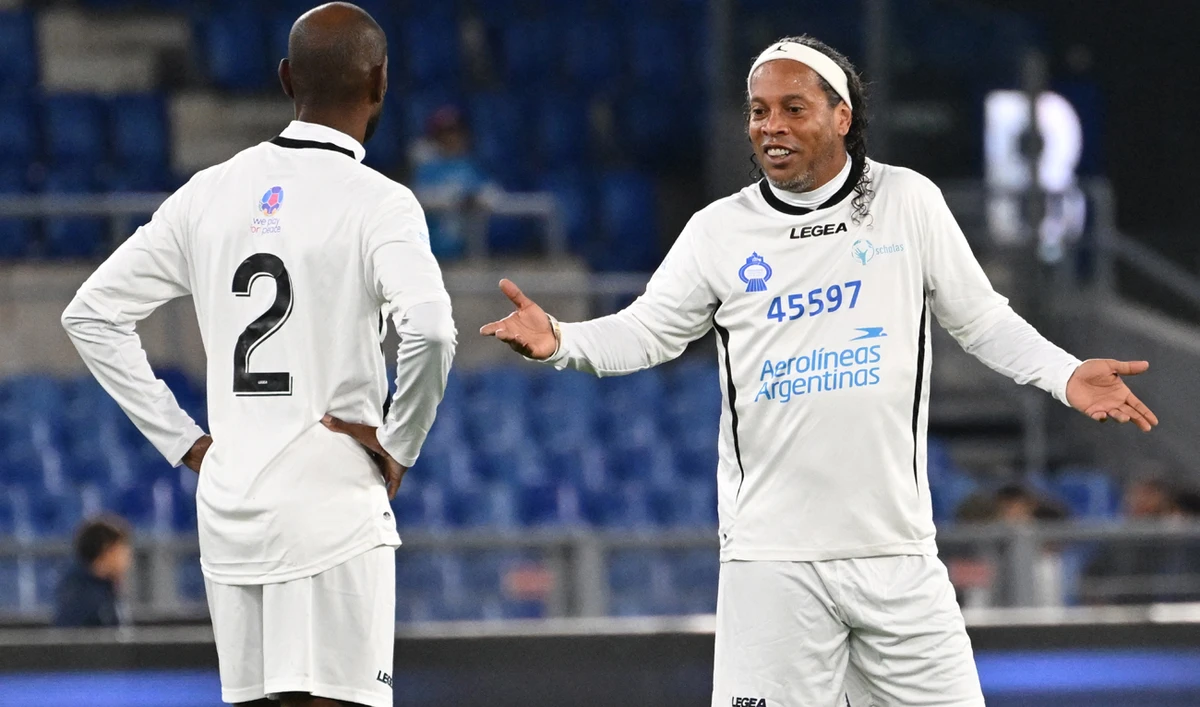 Former Brazilian player Ronaldinho (R) talks to former French player Eric Abidal during a friendly tribute "match for peace" in memory of late Argentininan player Diego Maradona, on November 14, 2022 at the Olympic stadium in Rome. (Photo courtesy: AFP)