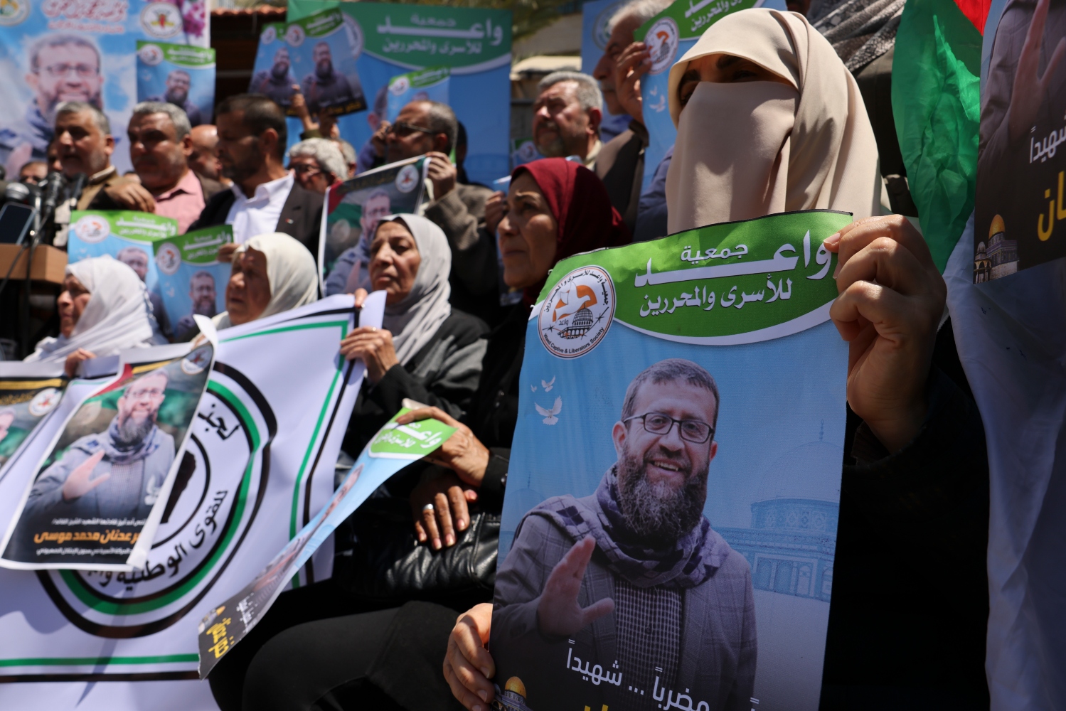 People hold portraits of Khader Adnan, who had been on a hunger strike, following the announcement of his death on May 2 (AFP)