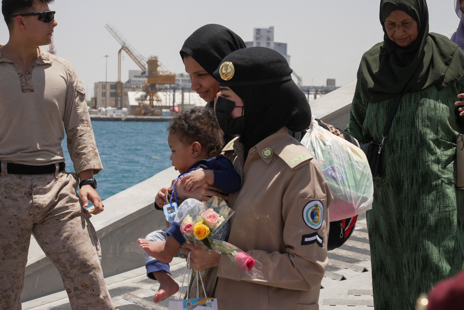 A Saudi Royal Navy female officer helps a woman disembark from a ship at the Jeddah Sea Port, Jeddah, Saudi Arabia, May 1, 2023. (Reuters)