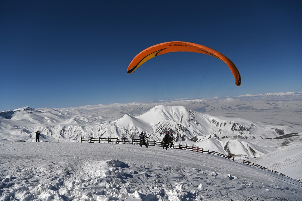 Above, a paraglider flies over the snow-covered mountain at Palandoken ski resort in Erzurum, eastern Turkey on March 4, 2021. (AFP file photo)