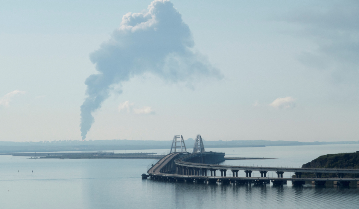 A view across the Kerch Strait shows smoke rising above a fuel depot near the Crimean bridge in the village of Volna in Russia's Krasnodar region as seen from a coastline in Crimea, May 3, 2023. (REUTERS)