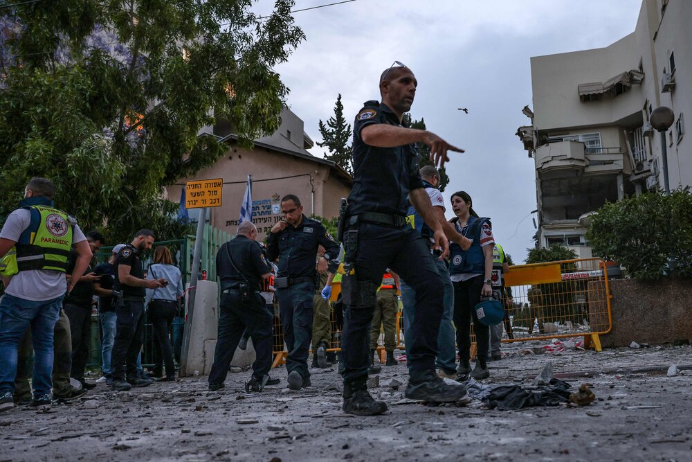 Israeli forces and rescuers gather near a building that was hit by a rocket fired from the Gaza strip, in Rehovot near Tel Aviv, on May 11, 2023. (AFP)