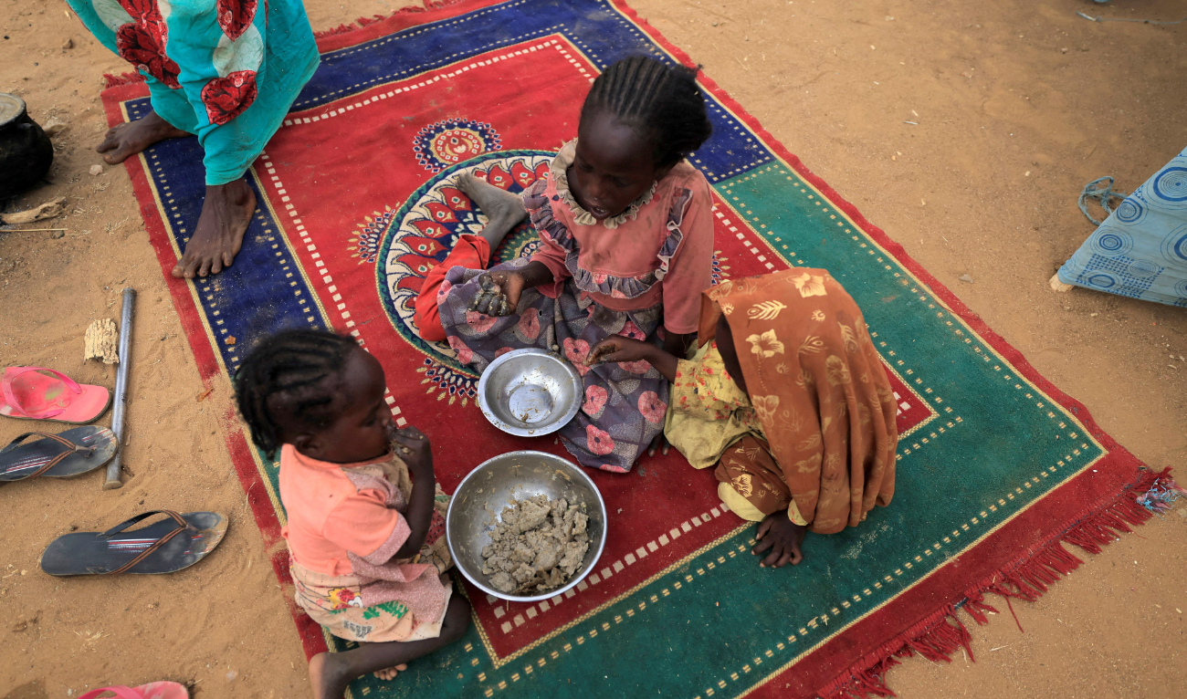 Sudanese refugee children who have fled the violence in Sudan’s Darfur region eat their breakfast beside makeshift shelters near the border between Sudan and Chad in Koufroun, Chad May 11, 2023. (Reuters)