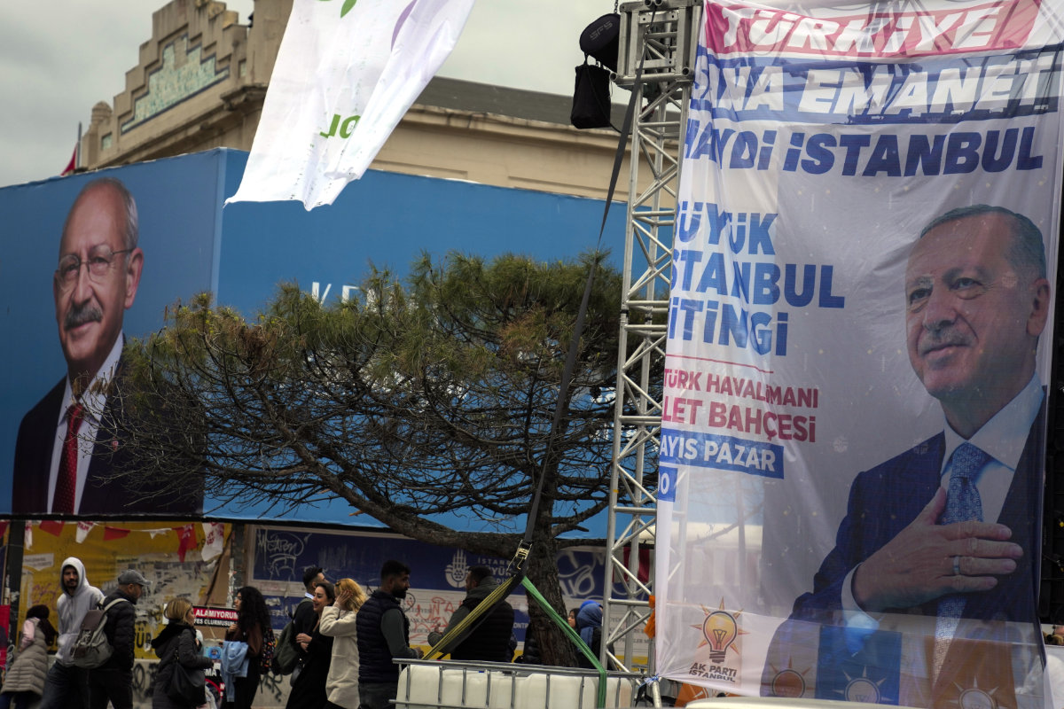 People walk next to billboards of Turkish President and People's Alliance's presidential candidate Recep Tayyip Erdogan, right, and Turkish CHP party leader and Nation Alliance's presidential candidate Kemal Kilicdaroglu in Istanbul on May 11, 2023. (AP)