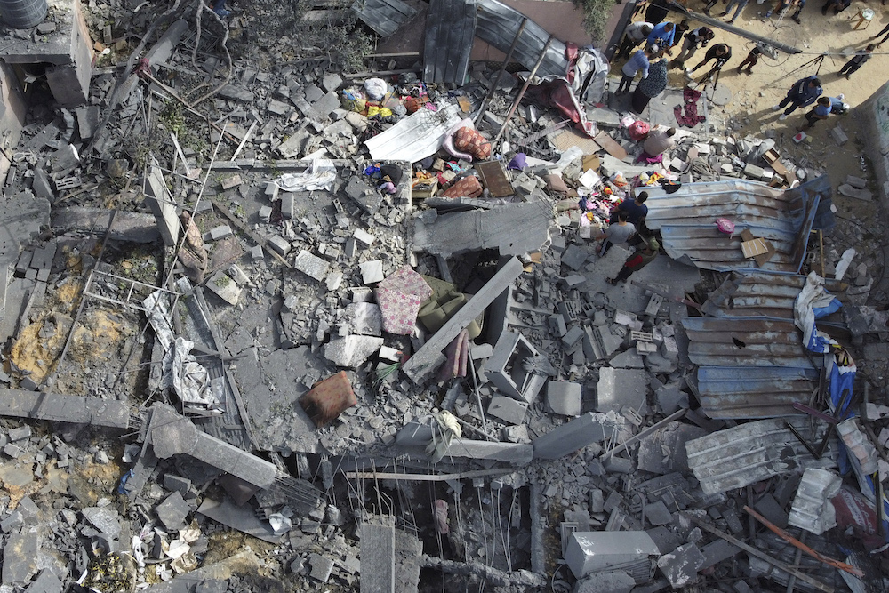 In this aerial picture people sift through the rubble of a building hit in an Israeli air strike in Beit Hanun, in the northern Gaza Strip (AFP)