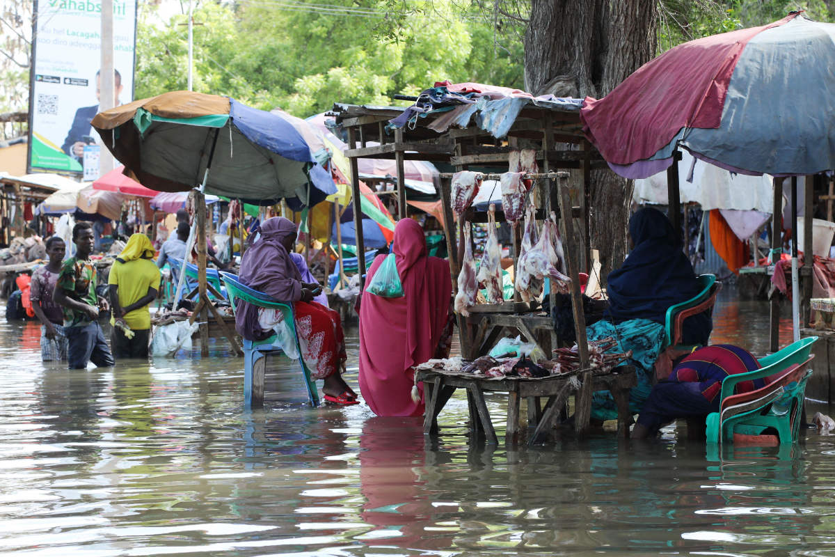 Vendors sit at their stalls in floodwater in Beledweyne, central Somalia, on May 12, 2023. (AFP)